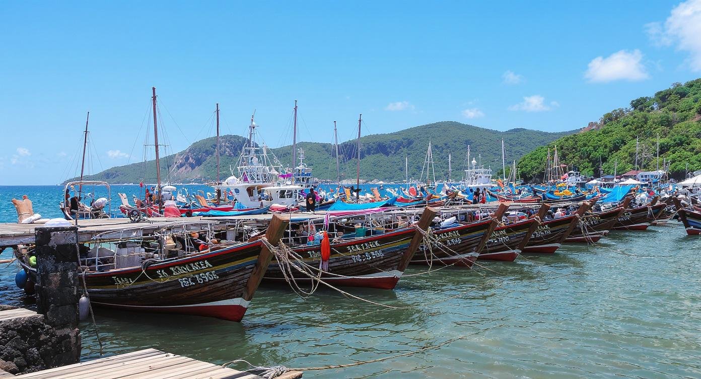 Labuan Bajo harbour port Flores Indonesia — colourful traditional wooden boats moored at jetty with green hills in background