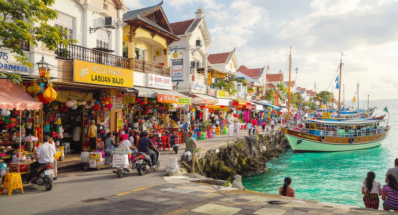 Labuan Bajo waterfront main street with motorbikes and local transport boats in harbour Flores Indonesia